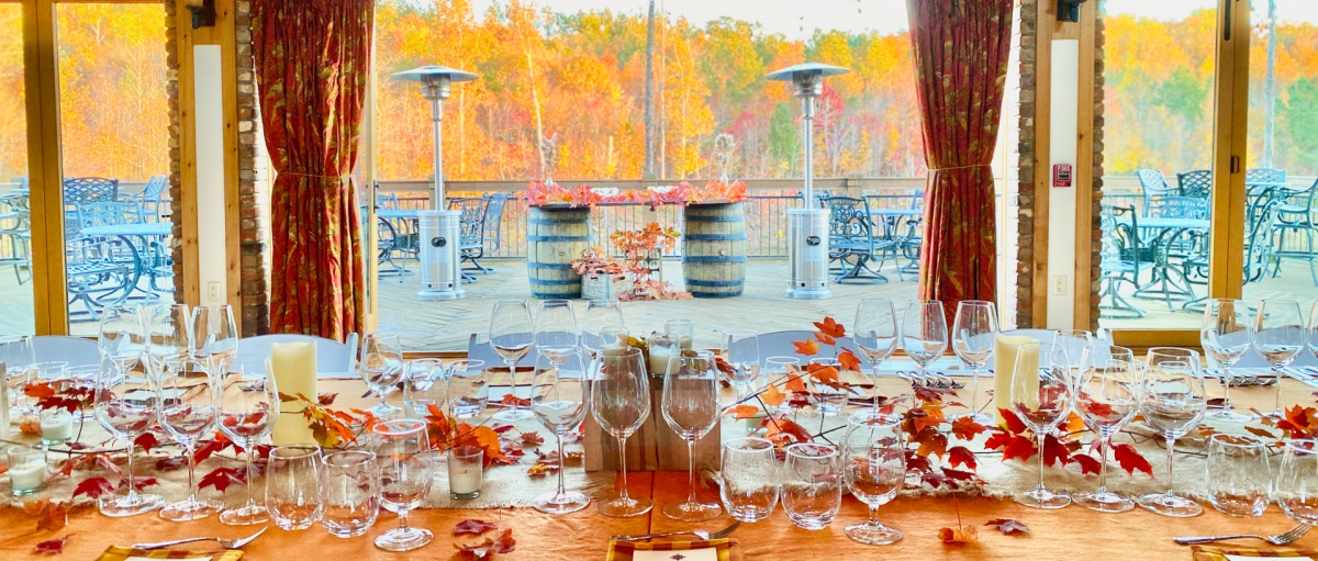 Wine glasses and cutlery lining table decorated for fall with patio in background