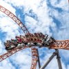 People on rollercoaster with blue sky in background.