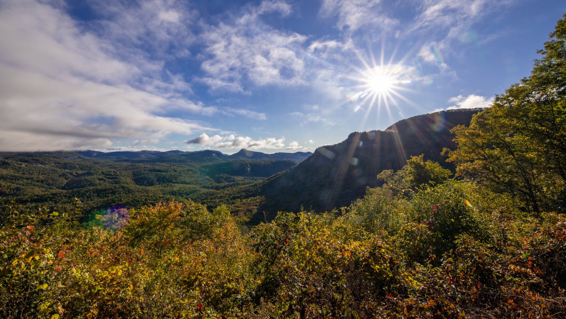 Sun shining brightly onto mountains and fall foliage