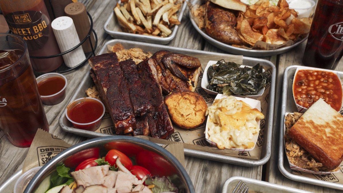 Overhead shot of plates of barbecue and sides plus Cheerwine on table