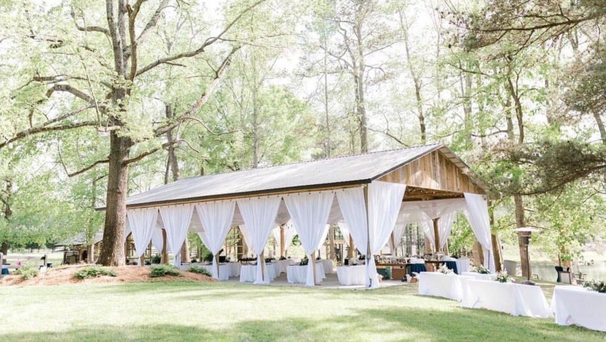 Wood pavilion with white drapes decorated for an outdoor wedding