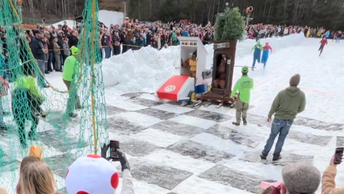 Crowd taking picture of Outhouse Races event on snowy hill