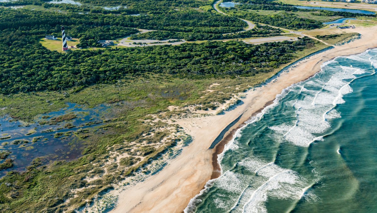 Aerial of national seashore terrain, beach, ocean and lighthouse