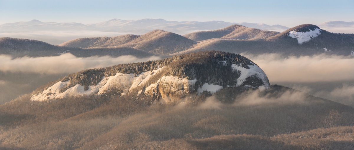 Looking Glass Rock in winter surrounded by other bare and snowy mountains