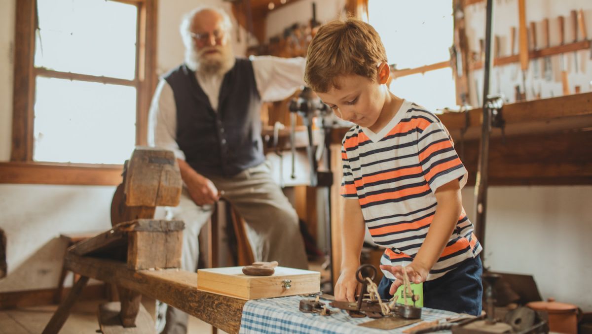 Kid playing in shop at Old Salem Museum with older man in background
