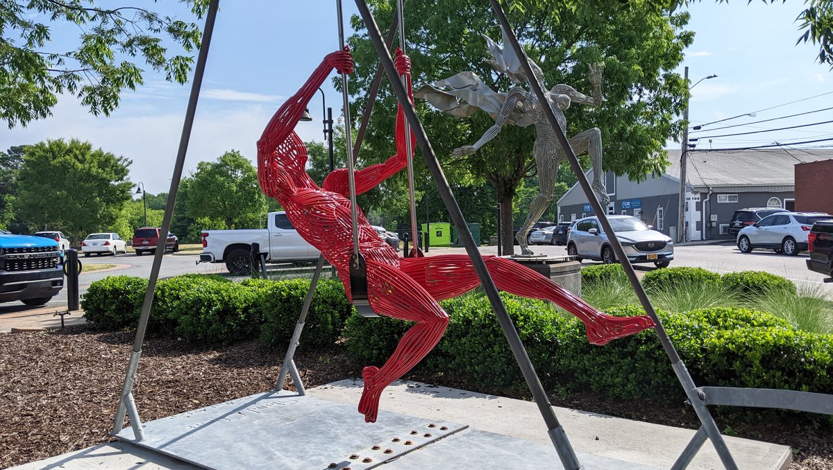 Metal art of humans in action in middle of small town during daytime