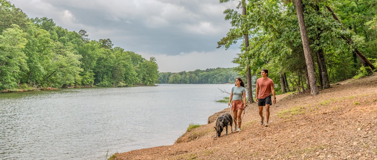 Couple walking dog along Badin Lake scenic path in Uwharrie National Forest.