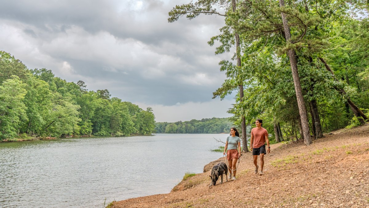 Couple walking dog along Badin Lake scenic path in Uwharrie National Forest.