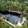 Aerial of quarry surrounded by trees with swimming platform in middle of water