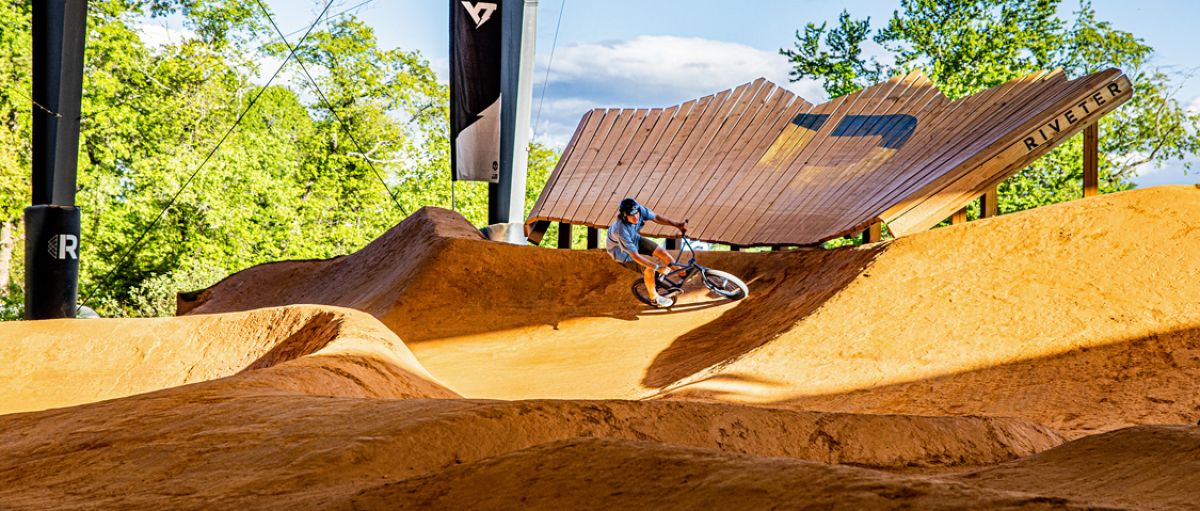 Person dirt biking on course with trees in background