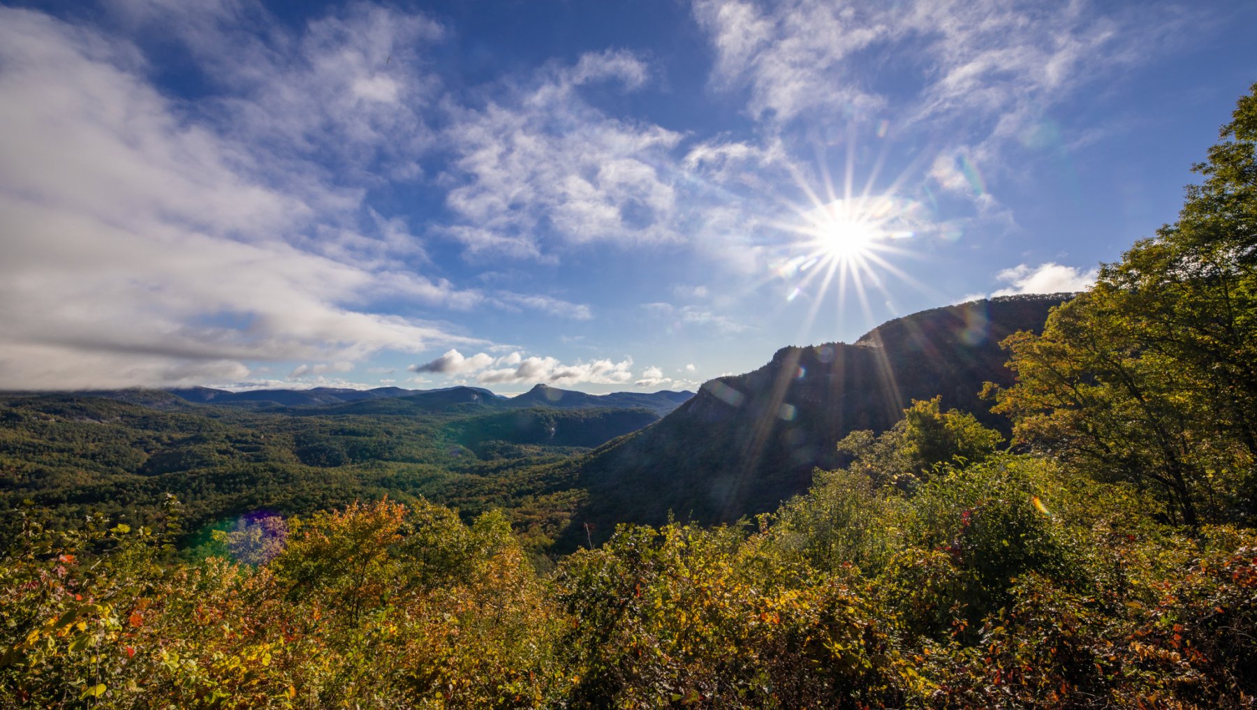 Sun shining bright over mountains and fall foliage