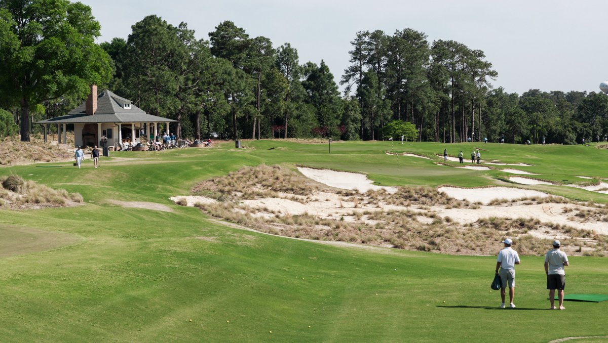 Golfers on greens and course with clubhouse-type building sitting on course.