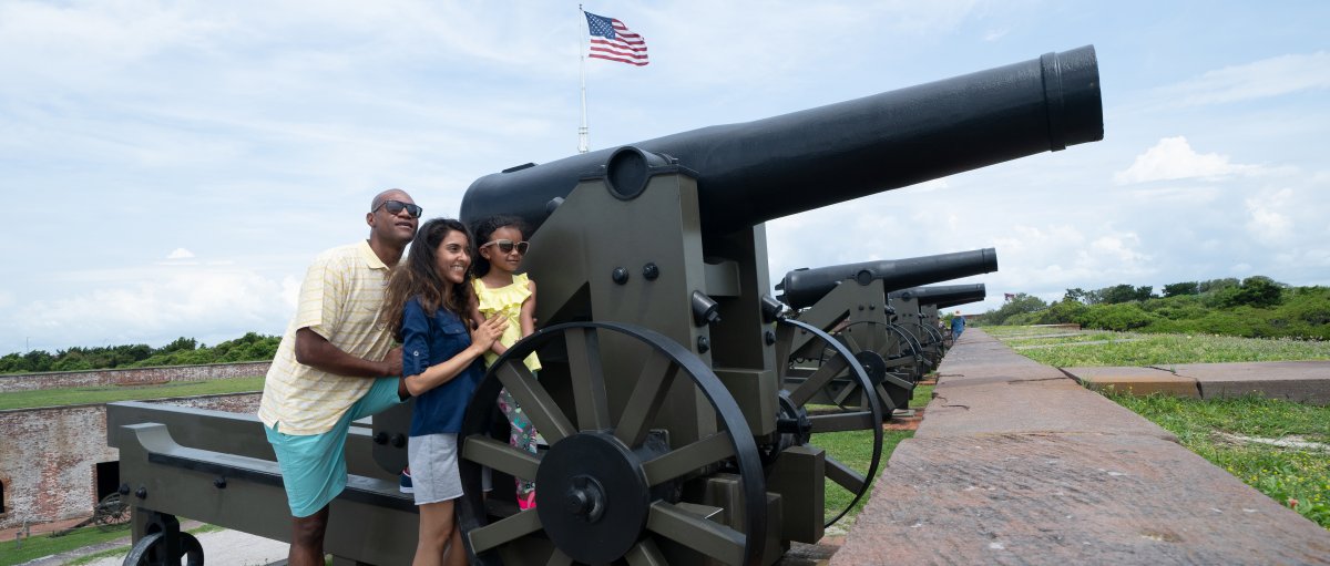 Family standing by canon at former military fort during daytime