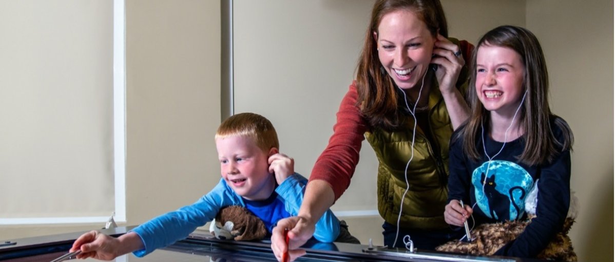 Mom and kids interacting with music table at museum