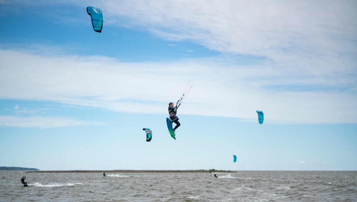 Several people kiteboarding on the Outer Banks with one airborne