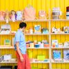 Woman browsing shelves at Port of Raleigh with bright yellow wall